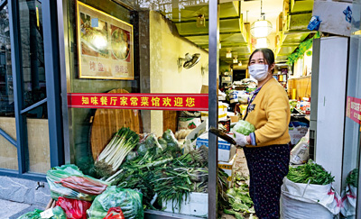 A woman arranges vegetables in her once-thriving restaurant that has been temporarily converted into a produce shop. Residents in Wuhan have been going out less since the epidemic broke out.