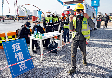 A construction worker puts on a mask he just received at a construction site for an emergency medical facility in Xi'an, capital of western China's Shaanxi Province, on February 3. The first phase of the facility, expected to be completed in 10 days, provides around 500 beds for quarantine wards. The total area of the facility is 33.33 hectares.