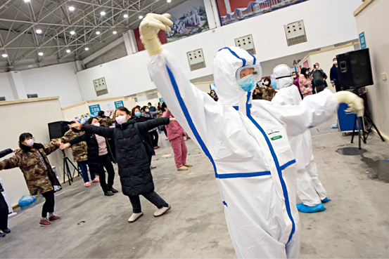 Doctors and nurses dance with patients in a cabin hospital converted from a cultural building complex dubbed “Wuhan Livingroom” on February 10. Exercise helps recovery and mental health.