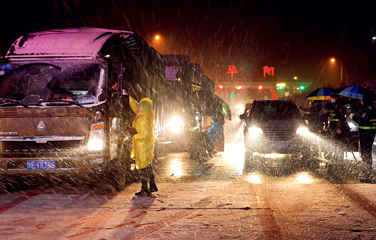 An officer checks a driver's temperature in snow at a checkpoint in Luonan County in western China's Shaanxi Province late on the night of February 5. Traffic police and health workers stayed on duty 24 hours across three shifts a day to screen passing drivers and vehicles to prevent the spread of the coronavirus.