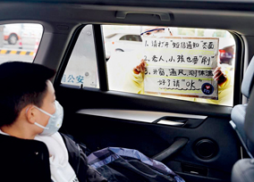 A volunteer guides a family in a car through a screening procedure at a checkpoint in Shanghai on February 14. A volunteer team worked around the clock in shifts to screen drivers, passengers and vehicles and spread knowledge of epidemic prevention at expressway checkpoints.
