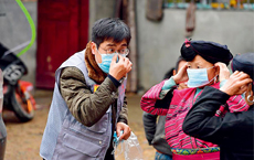 Yang Kai (left), an official from Jiangliu Village of Longsheng Ge Autonomous County in southwestern China's Guangxi Zhuang Autonomous Region, shows residents how to properly wear a mask on February 12.