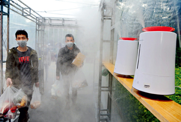 Returning residents pass through a “disinfecting lane” at the entrance of their residential blocks in Fuzhou, capital of Fujian Province, on February 11. Property management company set up this lane in which disinfectant is sprayed by humidifiers.