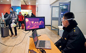 A staffer monitors the body temperature of travelers with an infrared thermometer at the exit of Beijing South Railway Station on February 6.