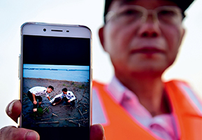 Hu Shibin, head of a patrol team monitoring the Yangtze River in Anqing, Anhui Province, displays a picture of a dead Yangtze cowfish (Finless porpoise) found on August 9, 2017. Since the end of June 2017, Hu’s team had patrolled the river several times a week. (LIU JUNXI)