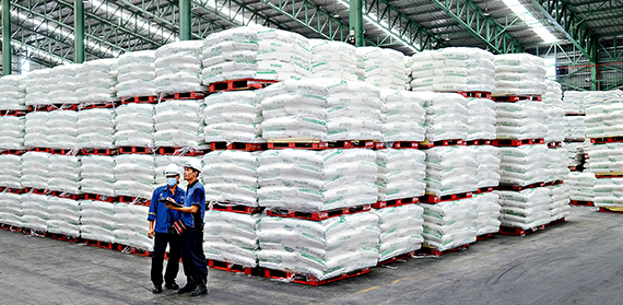 Two workers near piles of sugar bags in a factory in Johor，Malaysia，on August 21，2020.（BLOOMBERG）